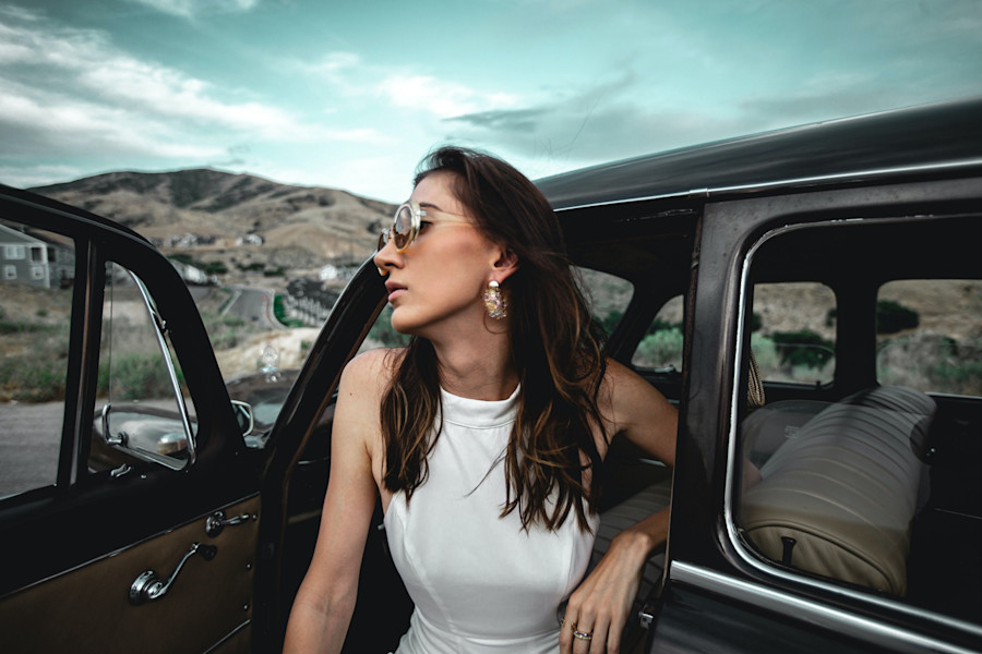 Woman in white dress in car wearing sunglasses long hair