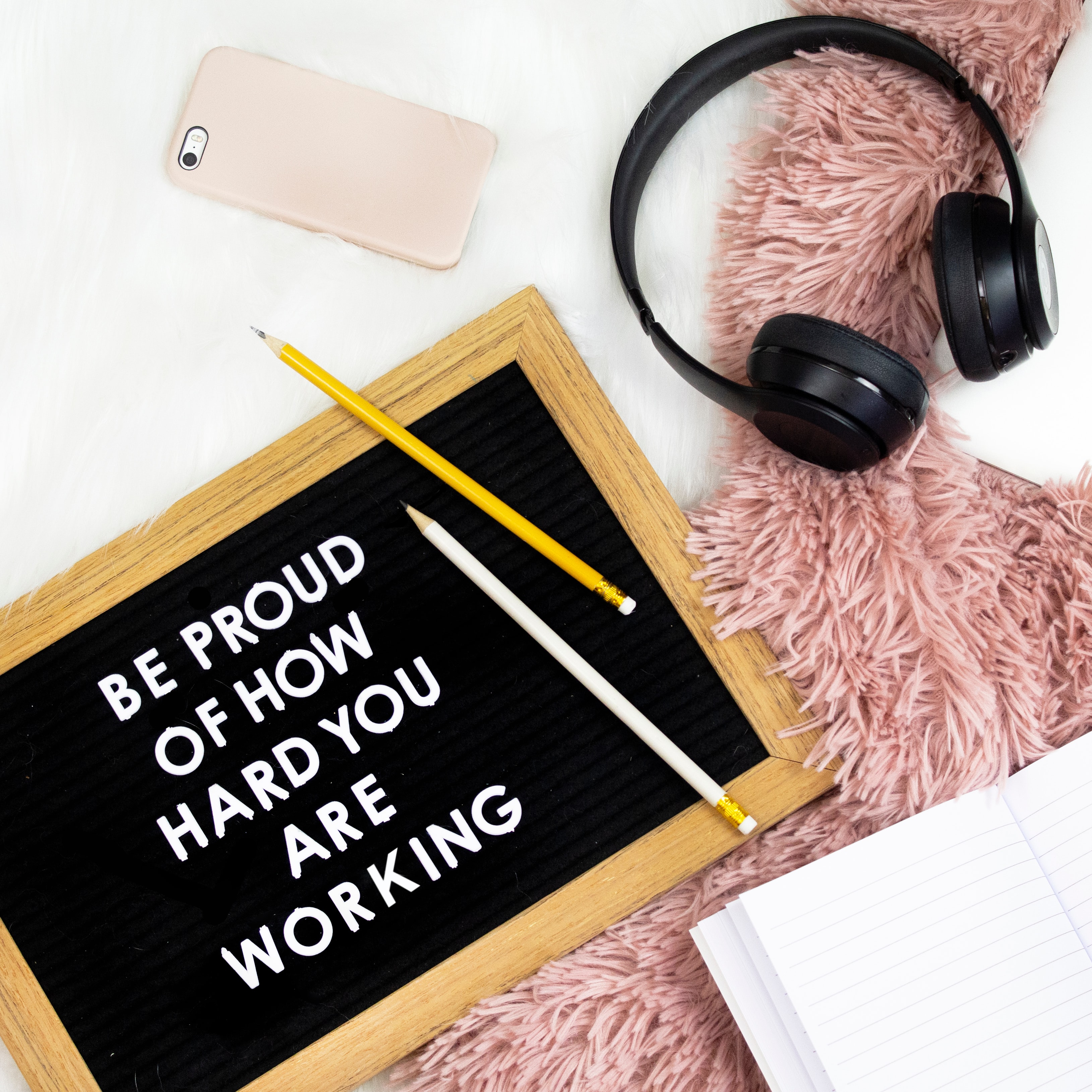 Be proud of how hard you are working sign with headphones and iPhone