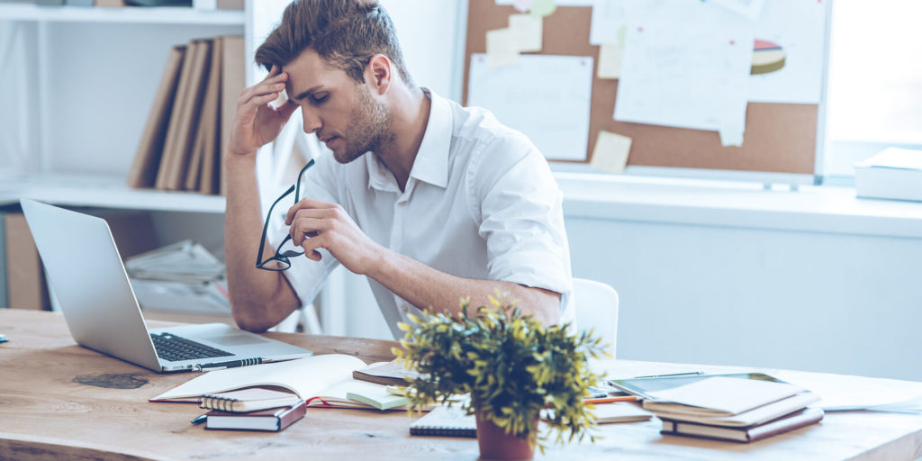 A man is working at his desk from home and seems stressed out