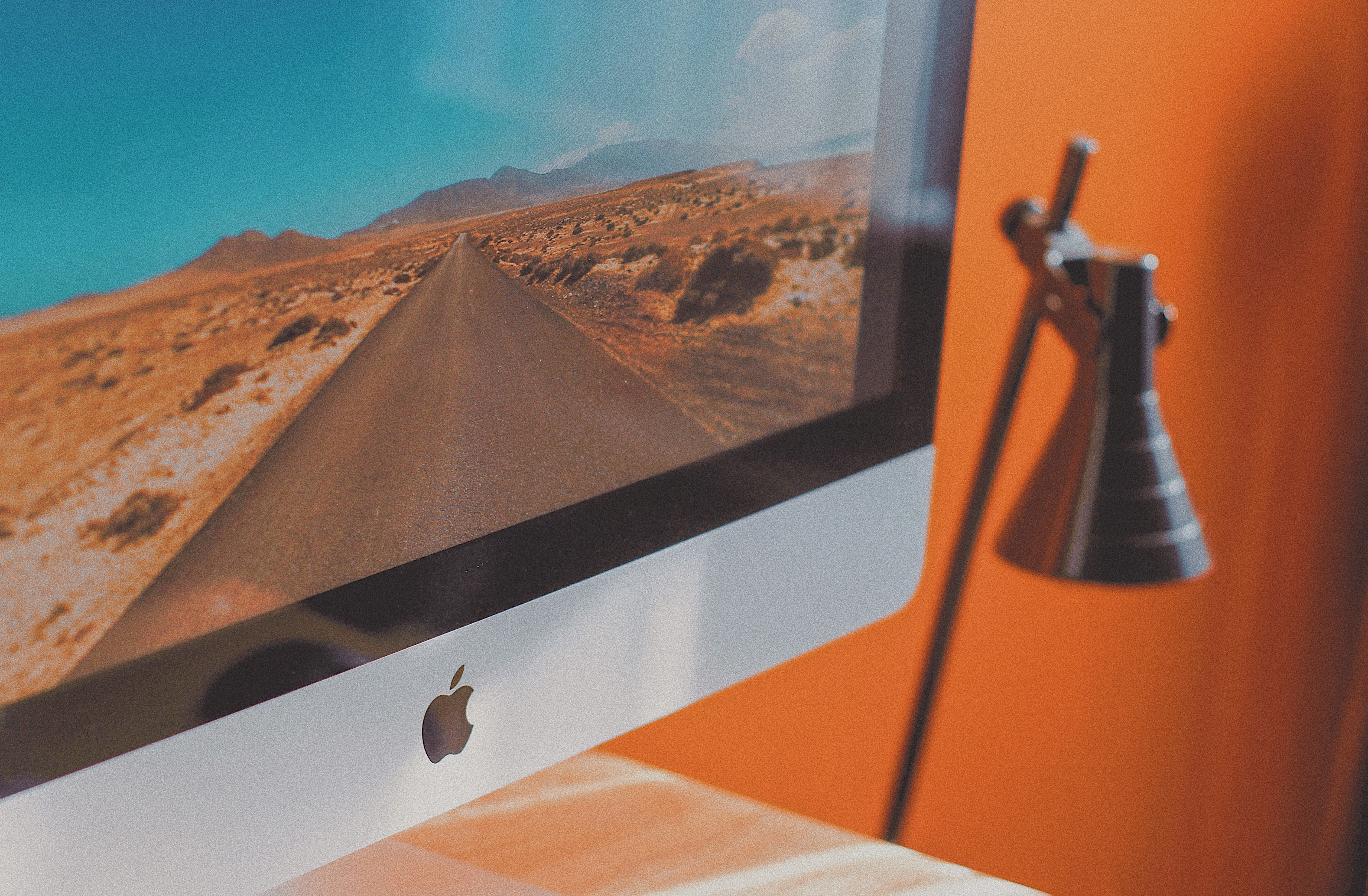 Apple desktop next to floor lamp.