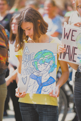 Girl holding smile to protect sign.