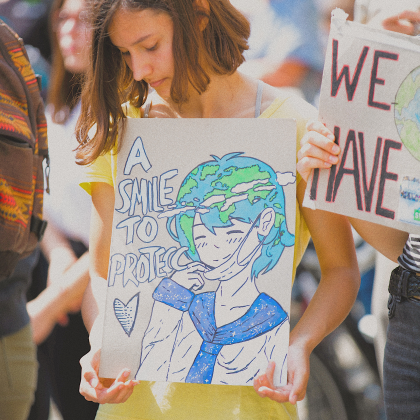 Girl holding smile to protect sign.