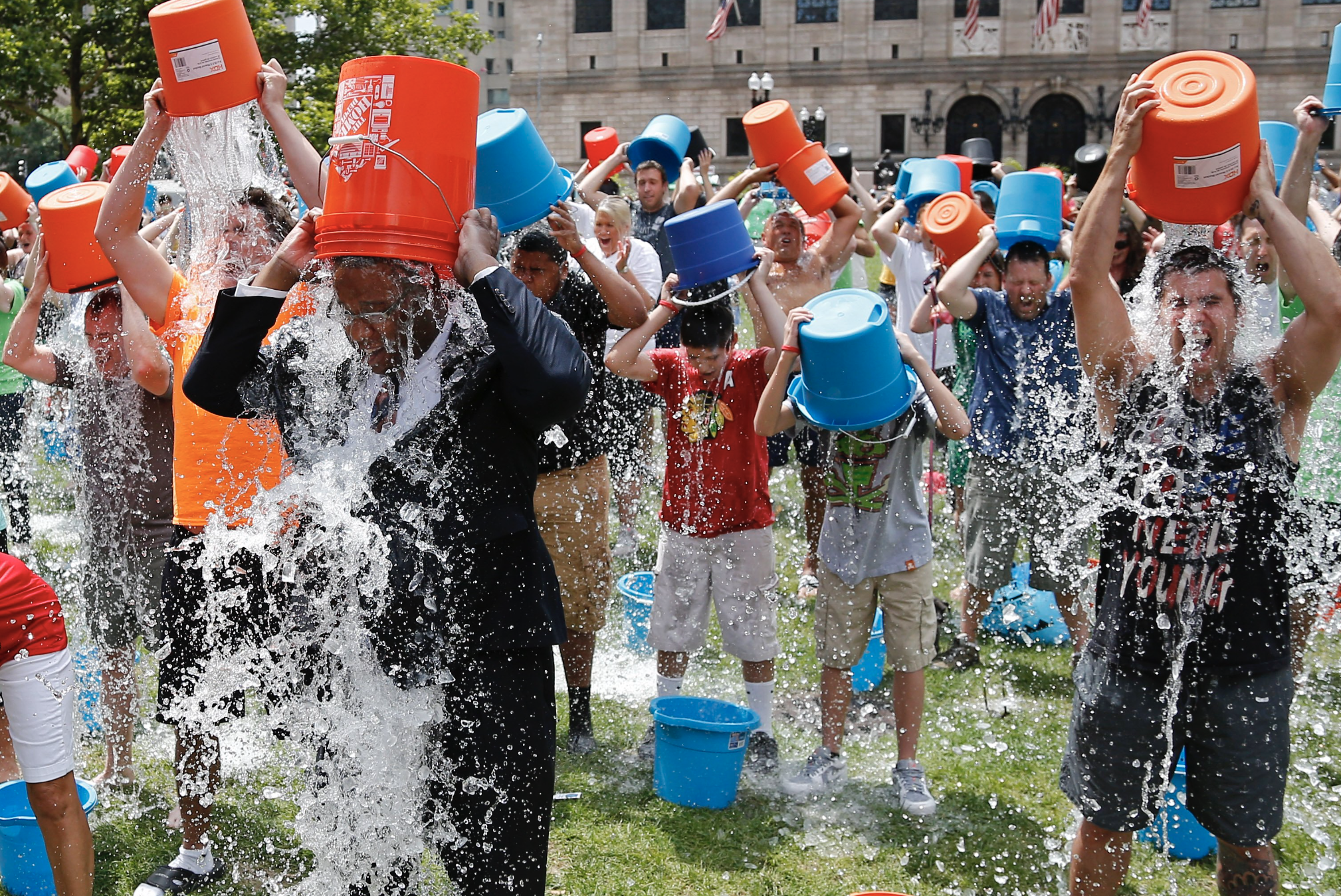 People participating in the ALS ice bucket challenge by dunking buckets of ice water over their heads.