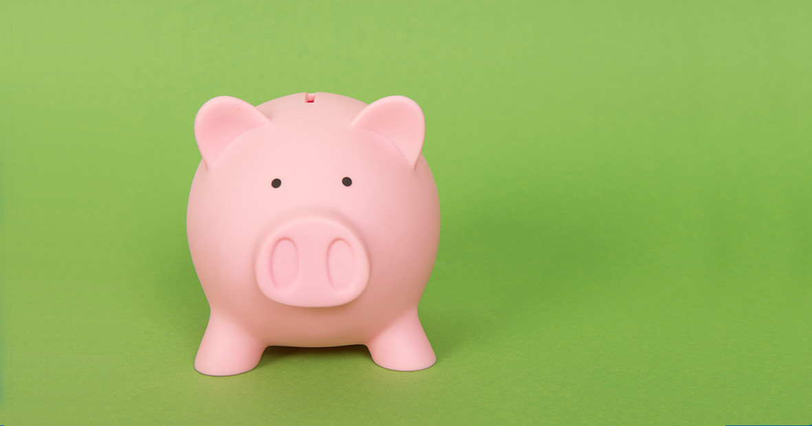 Pink piggy bank in front of a green background. 