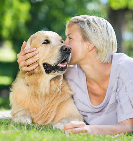 Lady laying in grass with golden retriever