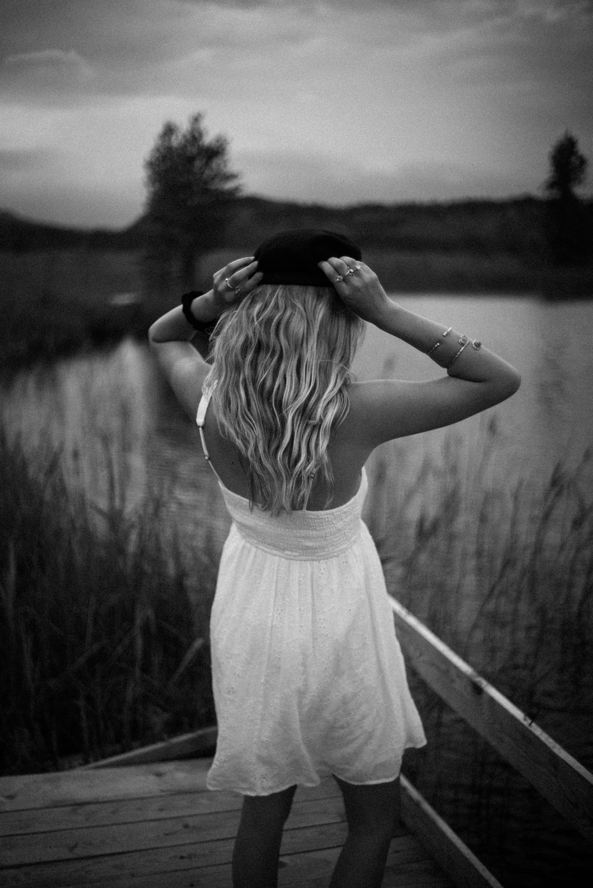 Gray scale photo of a woman standing near a body of water