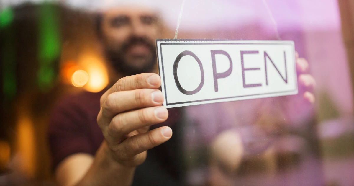 Business owner turning opening sign for the day | Swyft Filings