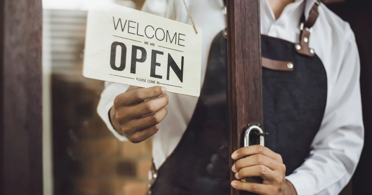 A small business owner hanging an open sign on the door | Swyft Filings