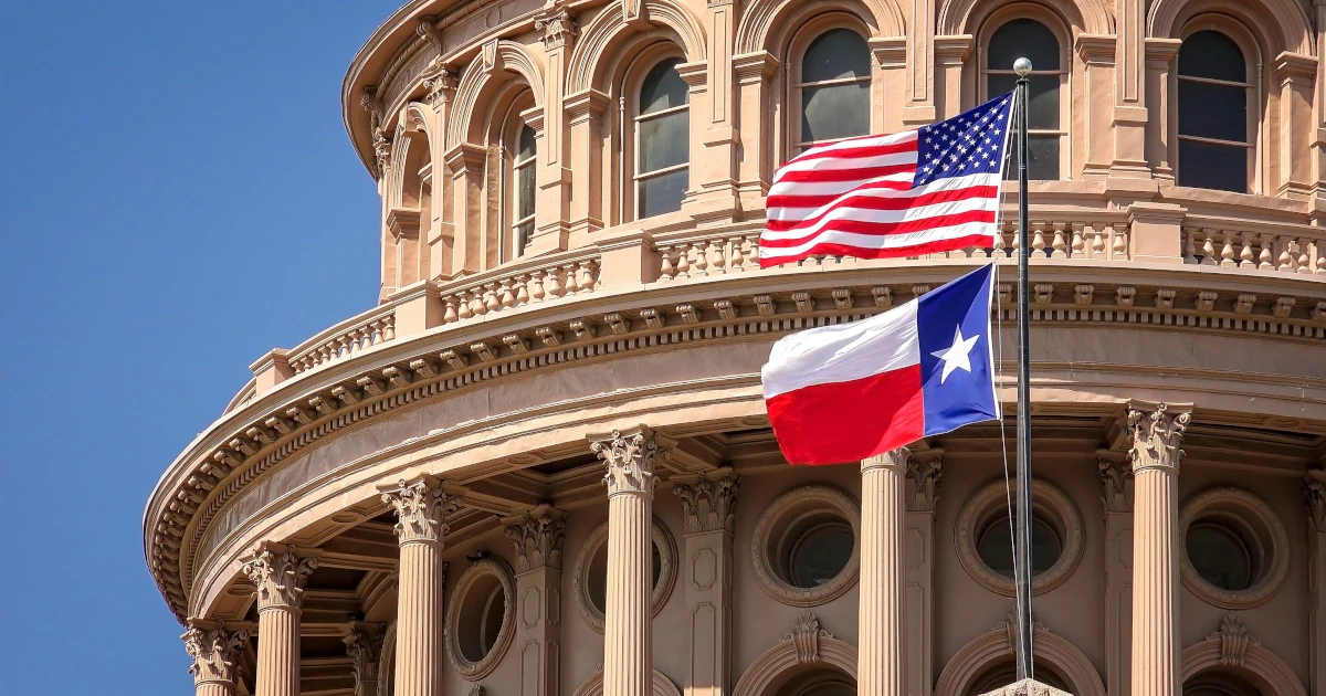 American and Texas state flags flying on the dome of the Texas State Capitol building in Austin