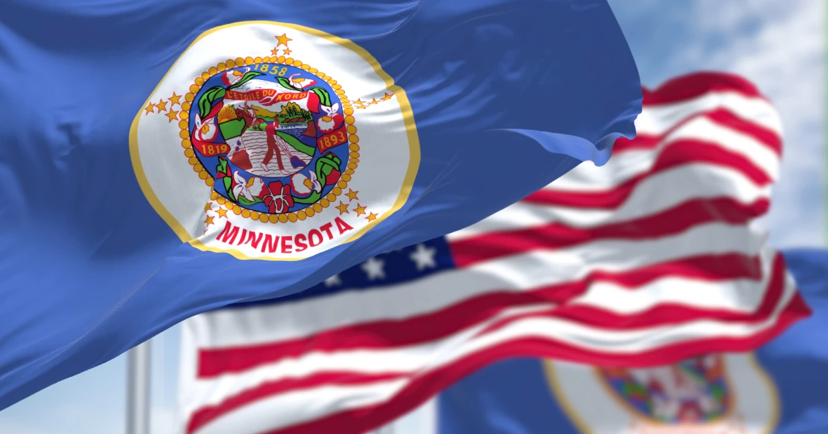 The Minnesota state flag waving along with the national flag of the United States of America