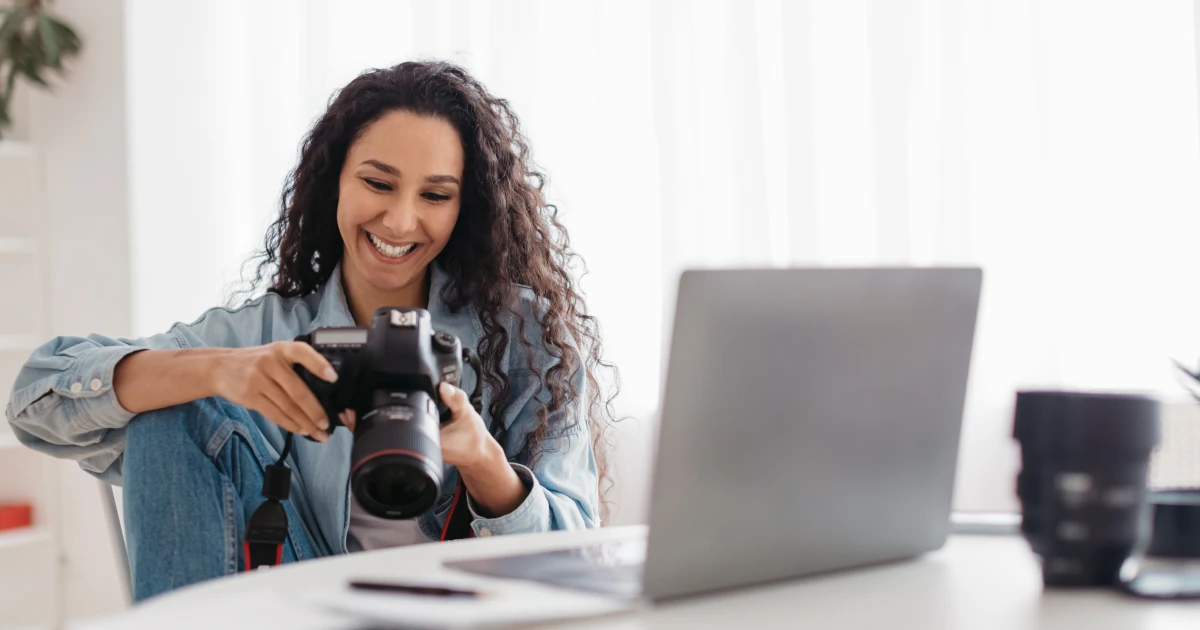 Woman photographer sitting at desk looking at photos in professional camera