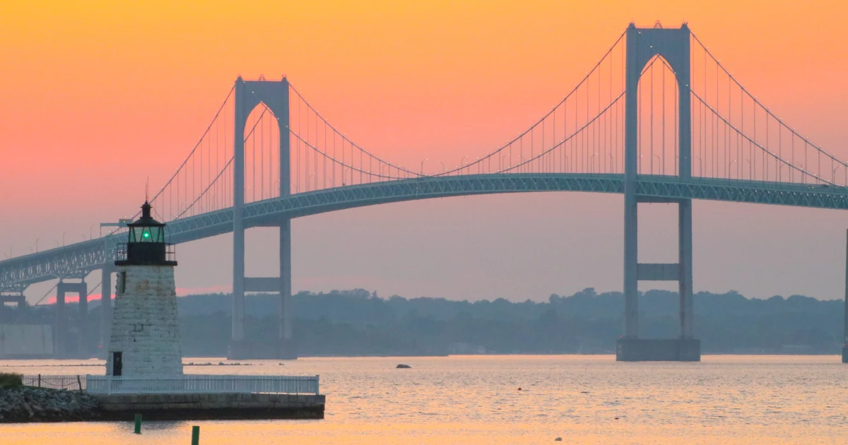 Newport Harbor Lighthouse and the Newport Bridge at sunset in Rhode Island