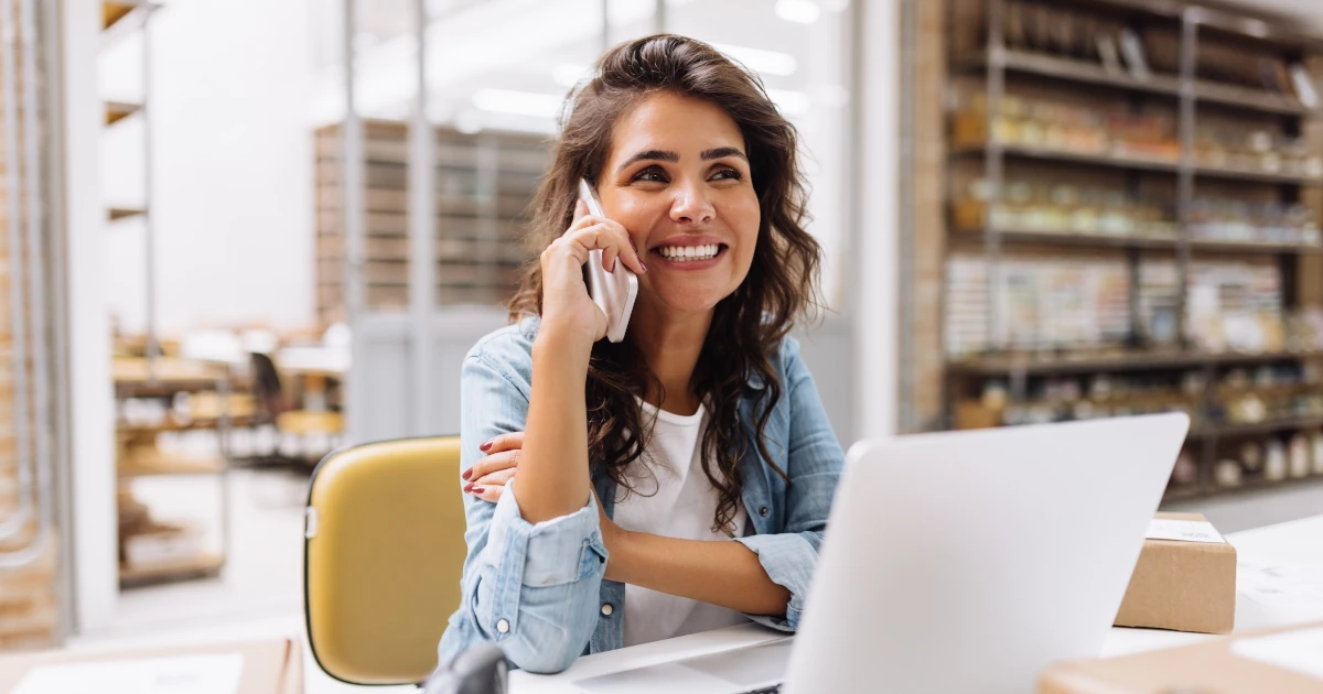 Cheerful businesswoman speaking on the phone while working in a warehouse