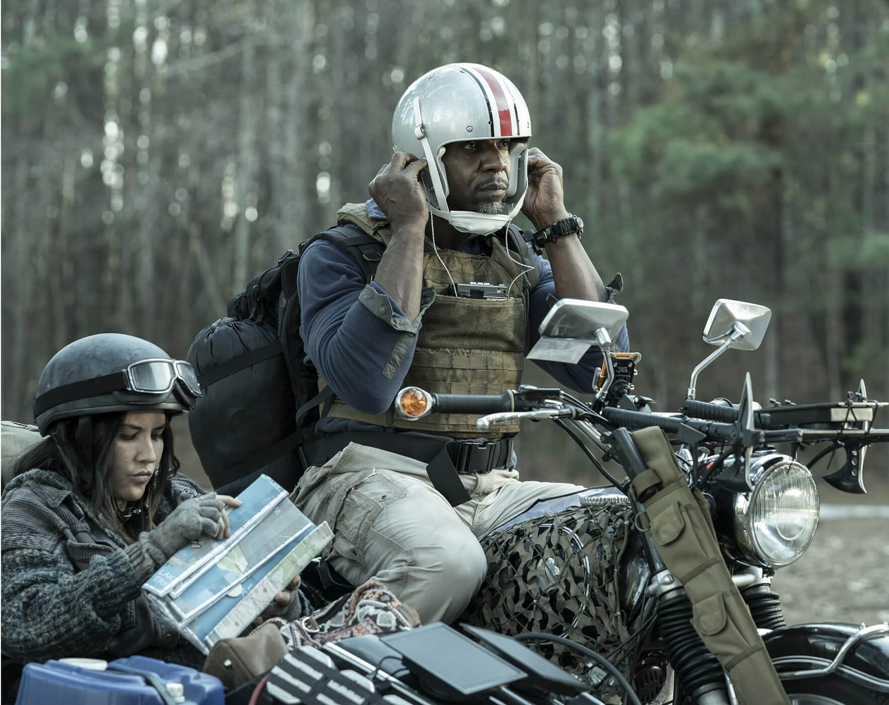 Man driving a motorcycle with a woman reading a map in the sidecar attached