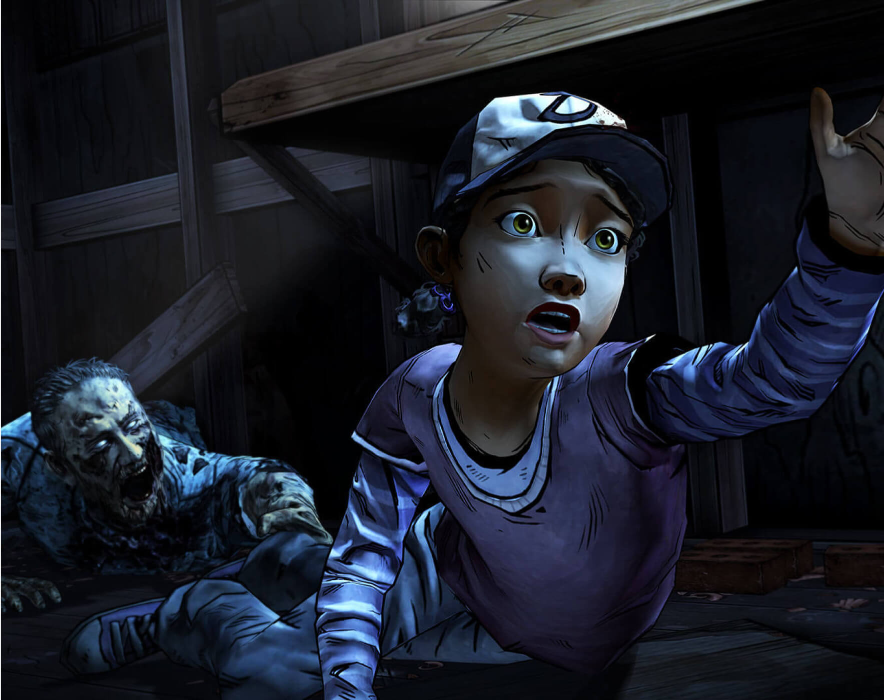 Clementine laying on the ground with her hand reaching out. Her foot is being held by a walker on the ground behind her.