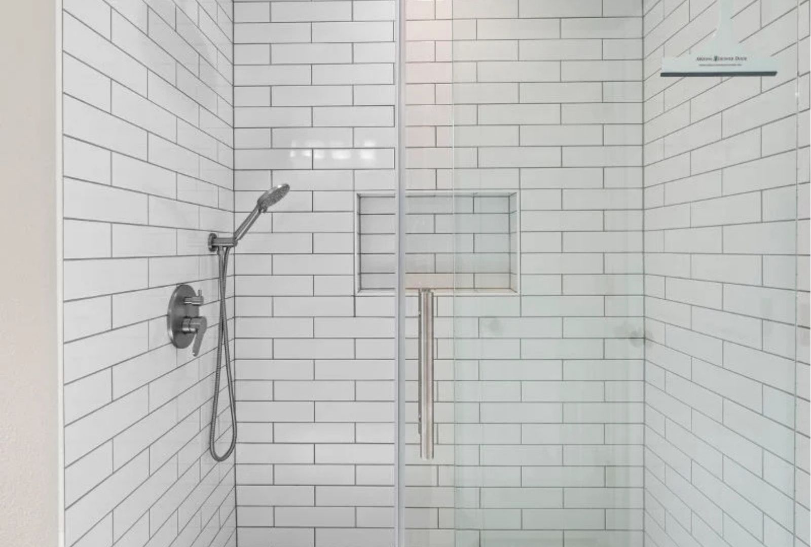 A modern shower with white subway tiles and a glass sliding door