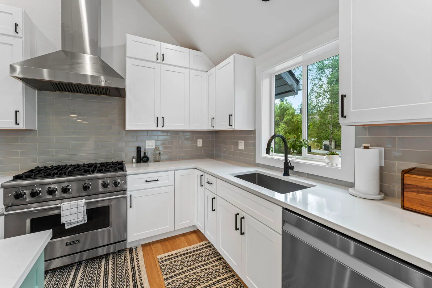 modern kitchen with white cabinets, a gray tiled backsplash, and a stainless steel range hood