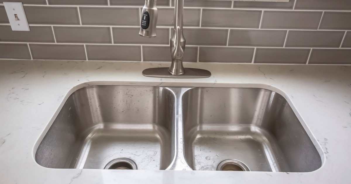 Double bowl stainless steel sink undermounted on the white kitchen countertop