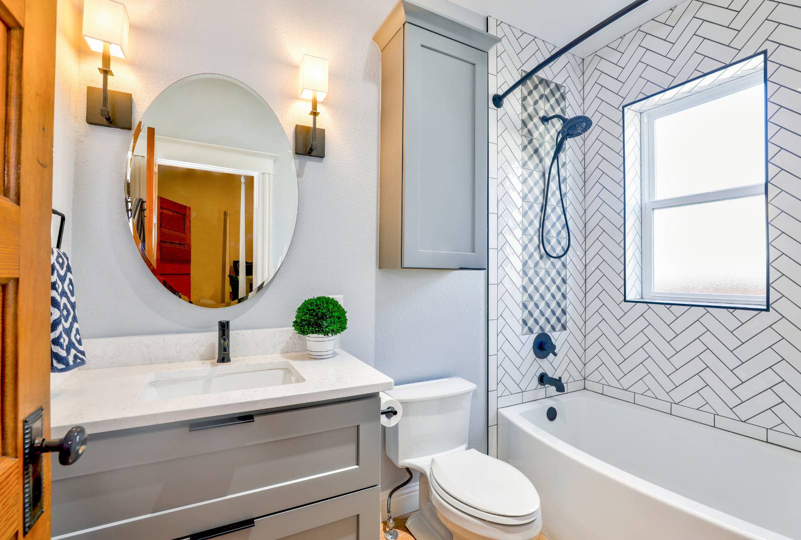 Oval Mirror and a vertical cabinet over Toilet Bowl