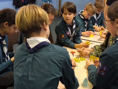 One Scout is demonstrating to the others how to make an origami star.