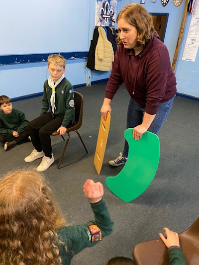 One of the Cub parents is showing the Cubs a couple of boards that wheelchair users can use to transfer themselves to or from their chair.