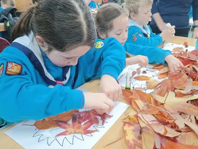 Three Beavers work intently on their leaf art, making hedgehogs and a fox.