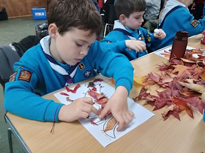 A Beaver concentrates as he glues leaves to his fox shape on his paper.