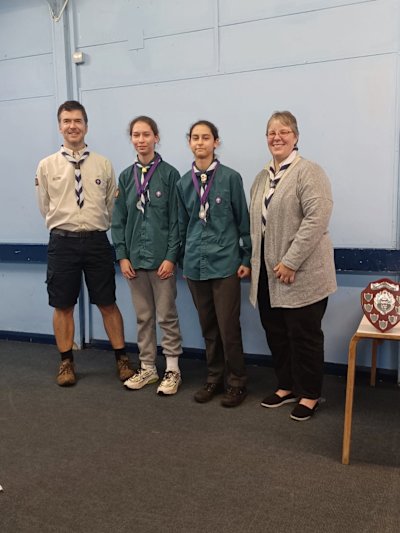 Two Scout girls stand proudly with their leaders, having received their runner-up medals.