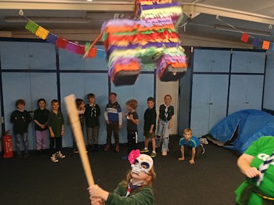 A Cub has hit the piñata, making it swing. The other Cubs watch for any sweets falling from it.