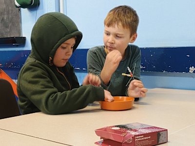 These two boys are helping each other with their beaded snowflakes.