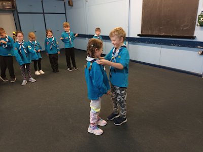 A Lodge Leader places the necker around a new member of his Beaver lodge. He's having a little giggle while he's doing it.