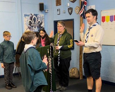 This young person is making his promise as a Scout, having finished Cubs.