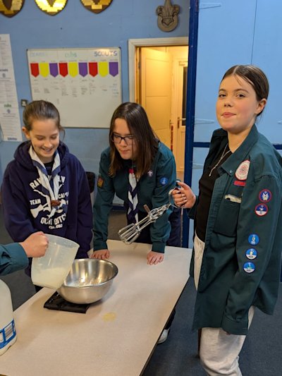 A group of Scout girls measures out the ingredients for their pancake batter. 