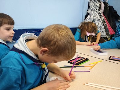 Several Beavers are working on their colouring, while two others look through the pencils for the right colour.