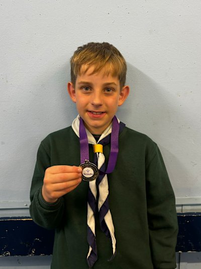 The runner-up Cub of the Year proudly shows off his medal, a smile on his face.