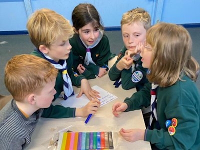 This Six looks really interested in what the story of their animation will be like. One Cub is writing their ideas down, while one tells the others her ideas. The other Cubs look on with interest.