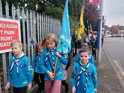 The Beaver flag bearer leads the parade toward the church, flanked by her colour guard. The flag bearers of the other sections are watching the tops of their flag poles, to make sure they don't catch on the tree branches overhanging the path.