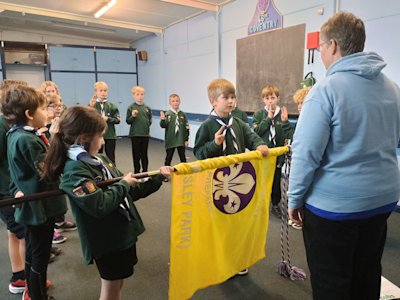 A new Cub makes the Scout sign with his right hand, his left hand on the Cubs flag held by his Seconder, while he says his Cubs promise.