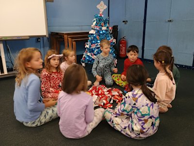 Still in their pyjamas, the Beavers are playing pass the parcel next to the Christmas tree, with a little something for everyone. There's a pile of torn wrapping paper in the middle of the circle.