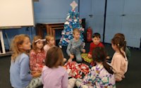 Still in their pyjamas, the Beavers are playing pass the parcel next to the Christmas tree, with a little something for everyone. There's a pile of torn wrapping paper in the middle of the circle.