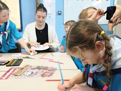 The Beavers are sat round the table, colouring in gift tags to use as decorations on their little tree, while a leader colours in a mandala to use as a star.