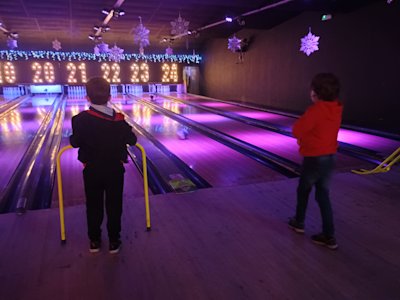 Two Cubs are watching their bowling balls head down the lane, hoping to knock down a few pins.