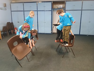 The Beavers are working as a team to pass the spare chair from the front to the back, moving their team closer to the finish line.