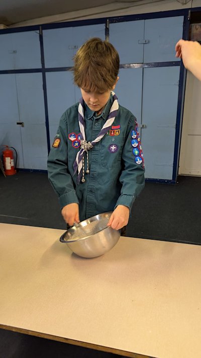 This Scout is carefully whisking his pancake mix.