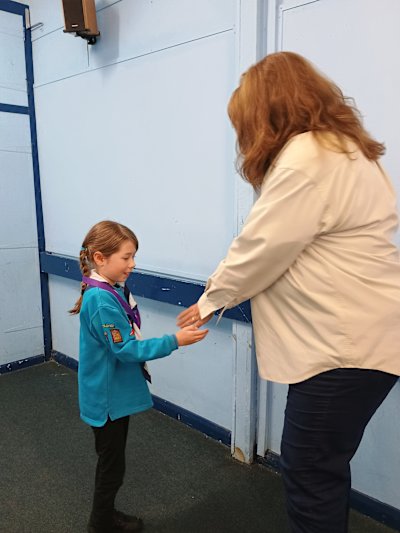 A Beaver smiles widely while having her hand shaked by her leader, after being awarded Runner-up Beaver of the Year.