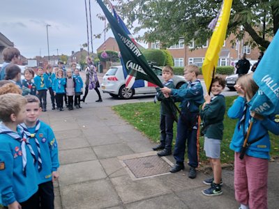 The flag bearers and colour guard stand either side of the walkway, while the remaining Beavers, Cubs and Scouts prepare to enter the church between them. The Cubs flag bearer looks particularly pleased with himself.