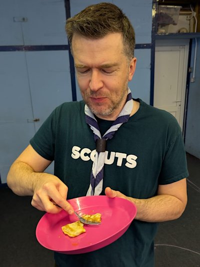 Looks like this Scout leader has found a Scout willing to make him a pancake and he's scoffing it as quick as he can!