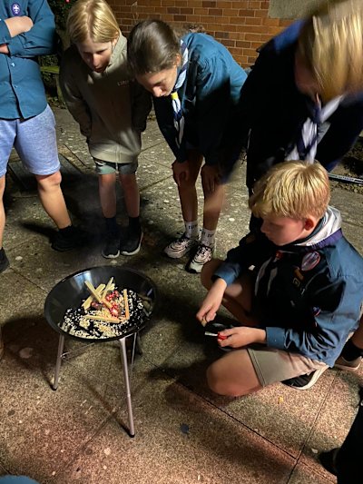 Four Scouts watch their appointed teammate attempt to get a fire started using a ferro rod, striker, cotton wool, sawdust and tinder wood. He managed to be the first to get the tinder to stay lit!