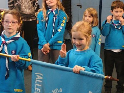 A new Beaver says her promise for the first time, her left hand on the Beavers flag her Assistant Lodge Leader is holding.