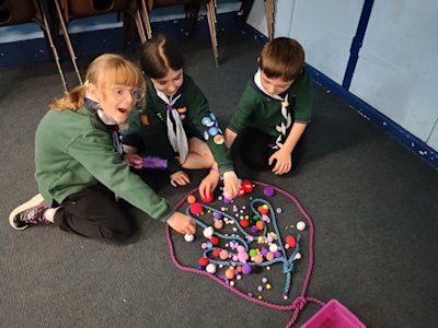 These Cubs have used a lot of pom poms to create their very colourful version of a fleur-de-lis. One seems very excited by it.